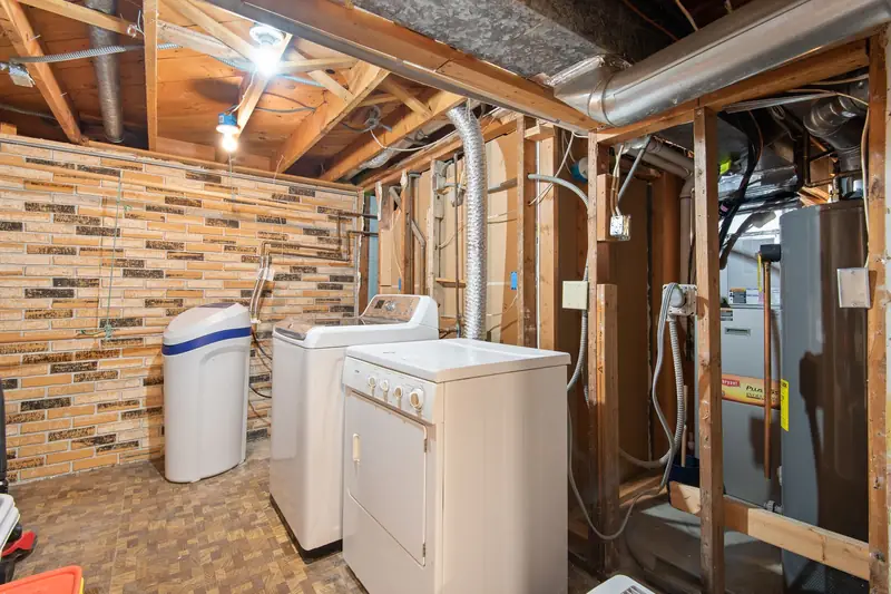 Basement utility area with a tank water heater and furnace next to a washer, dryer and water softener