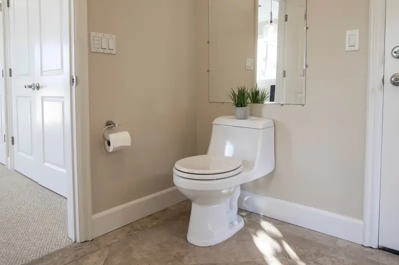 Clean bathroom with a white toilet, tile floor and a small window