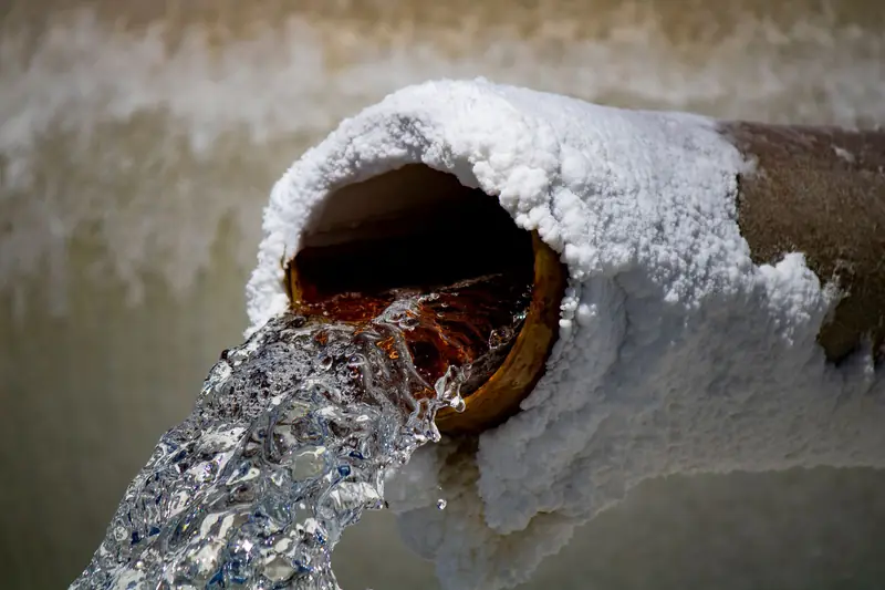 Water gushing out of the broken end of an old, crusted pipe