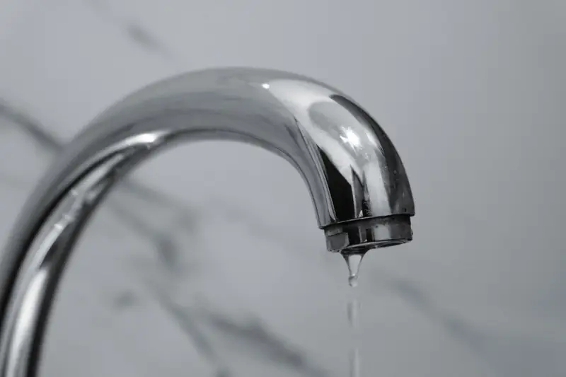 Water dripping from the spout of a chrome bathroom faucet