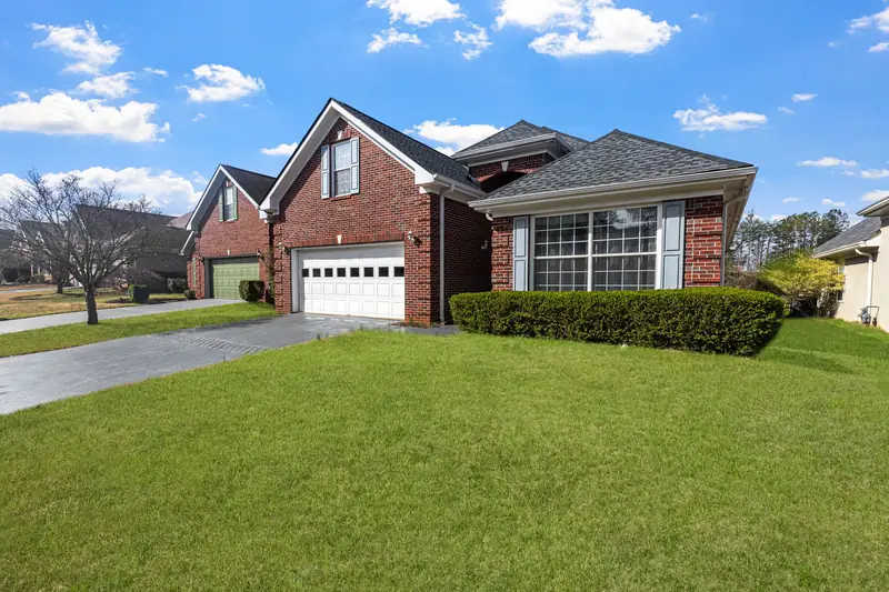 Red brick house with a green front lawn under a blue sky