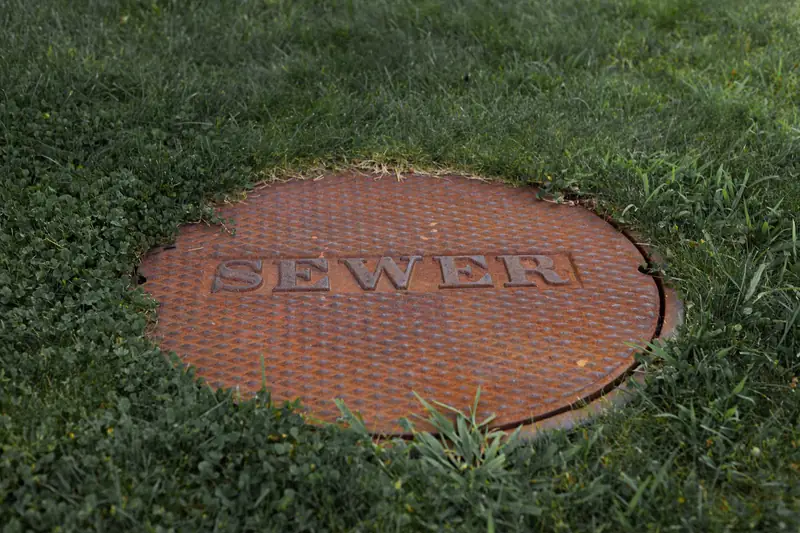 Rusty sewer access cover set in a grassy lawn