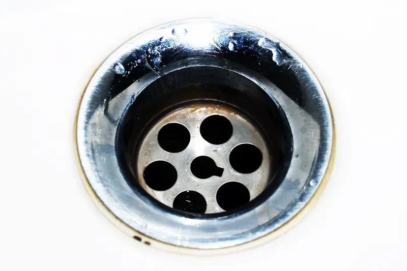 Close-up of a stainless steel sink drain with water droplets
